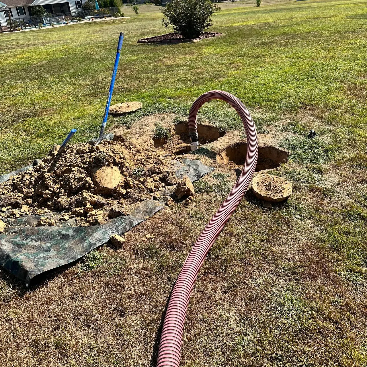 Septic tank lids dug up in a lawn with the pump hose in place