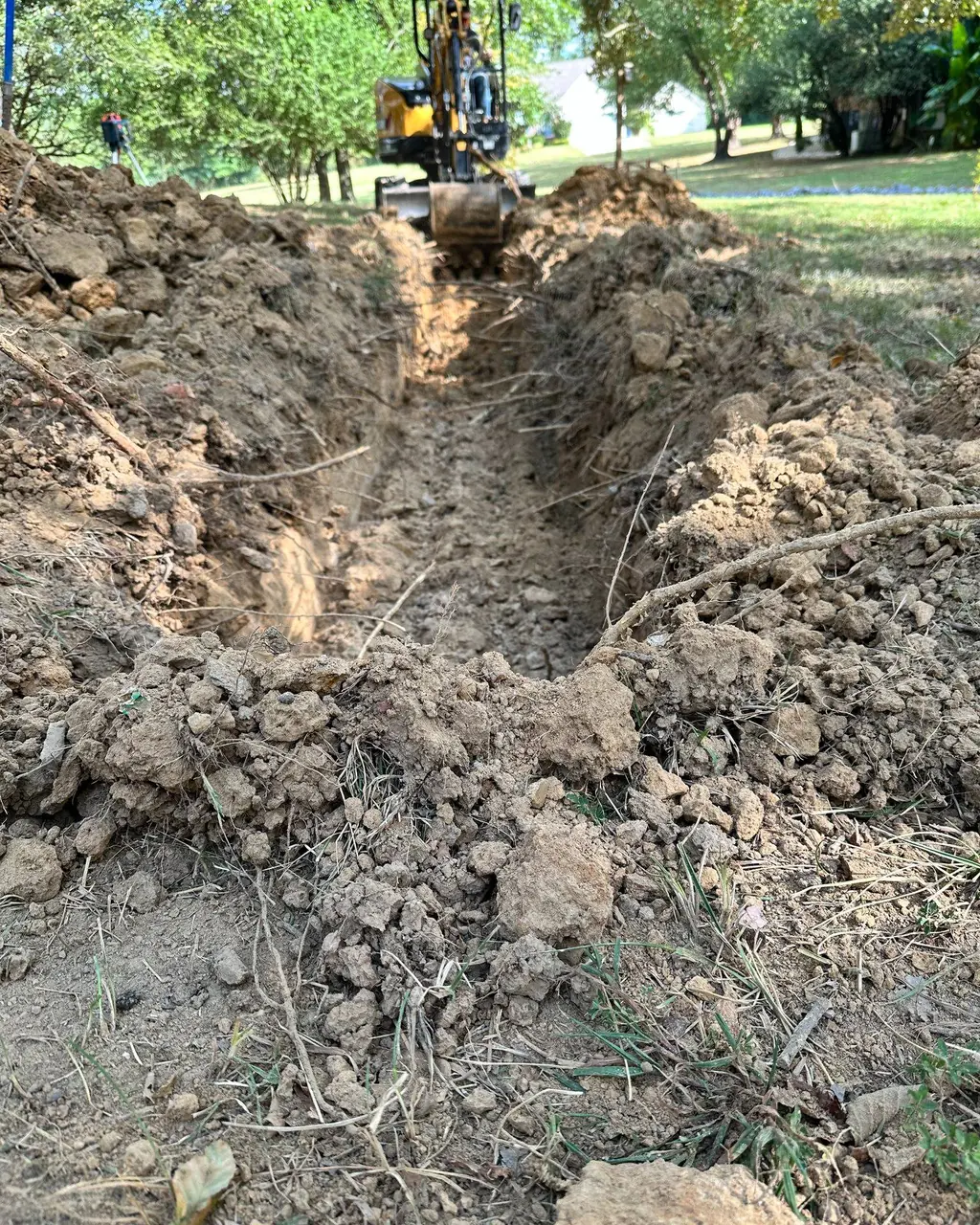 A freshly dug trench with the excavator working beyond it