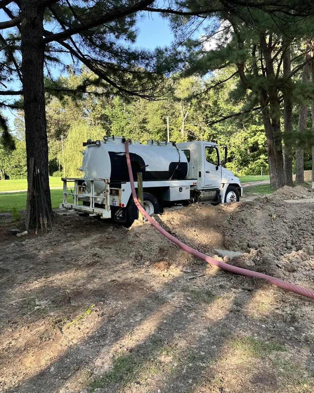 The Wurth Brothers pump truck pumping a septic tank in a wooded yard